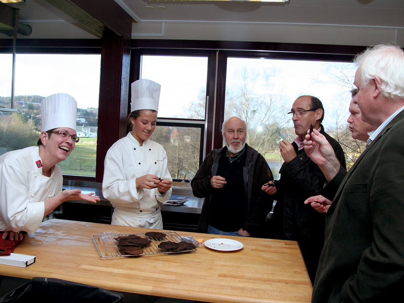 VNR-leder Per C. Aarsand (f.h), rektor Erik Strøm, Ivar Steinsland og Karstein Bjørge fra Sund kommune fikk smake blodpannekaker utviklet av elevene ved restaurant- og matfaglinjen på Sotra Vidaregåande Skule. Faglærer Eva Danielsen og elev Ane Berland.